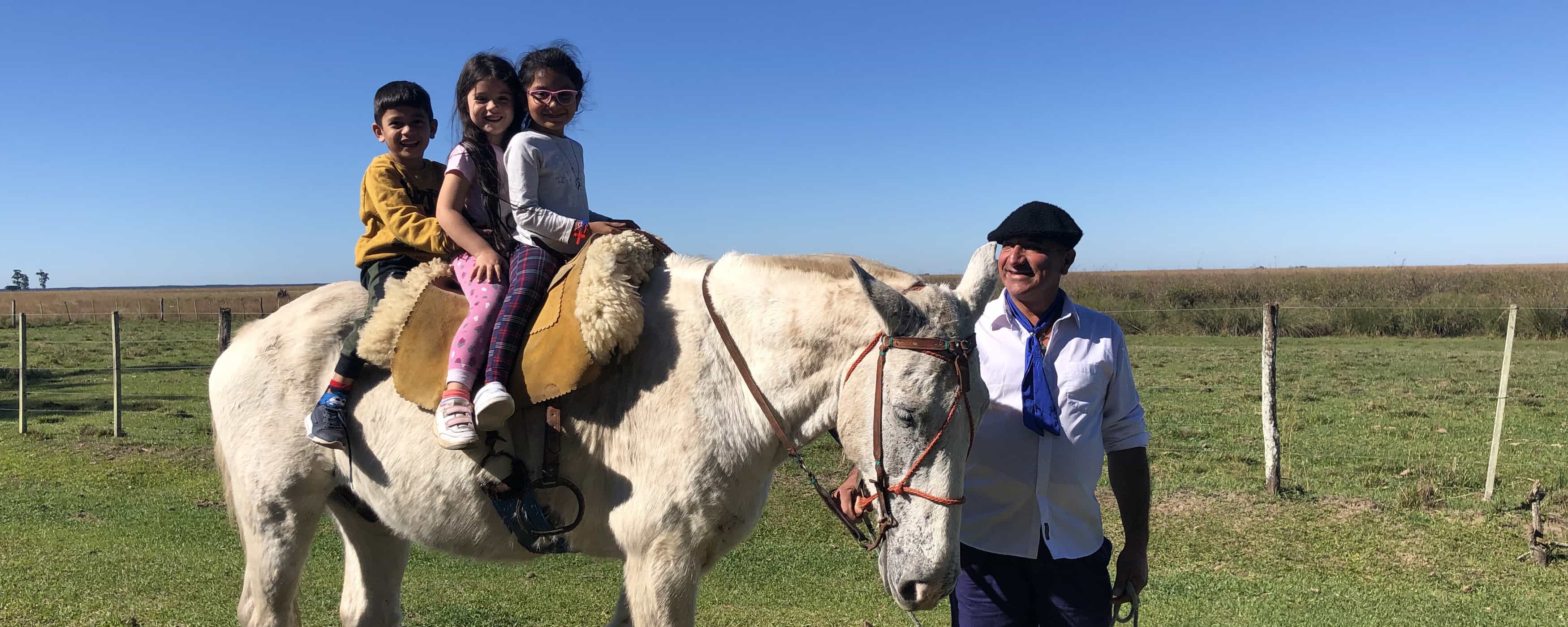 photo of three children on a pony
