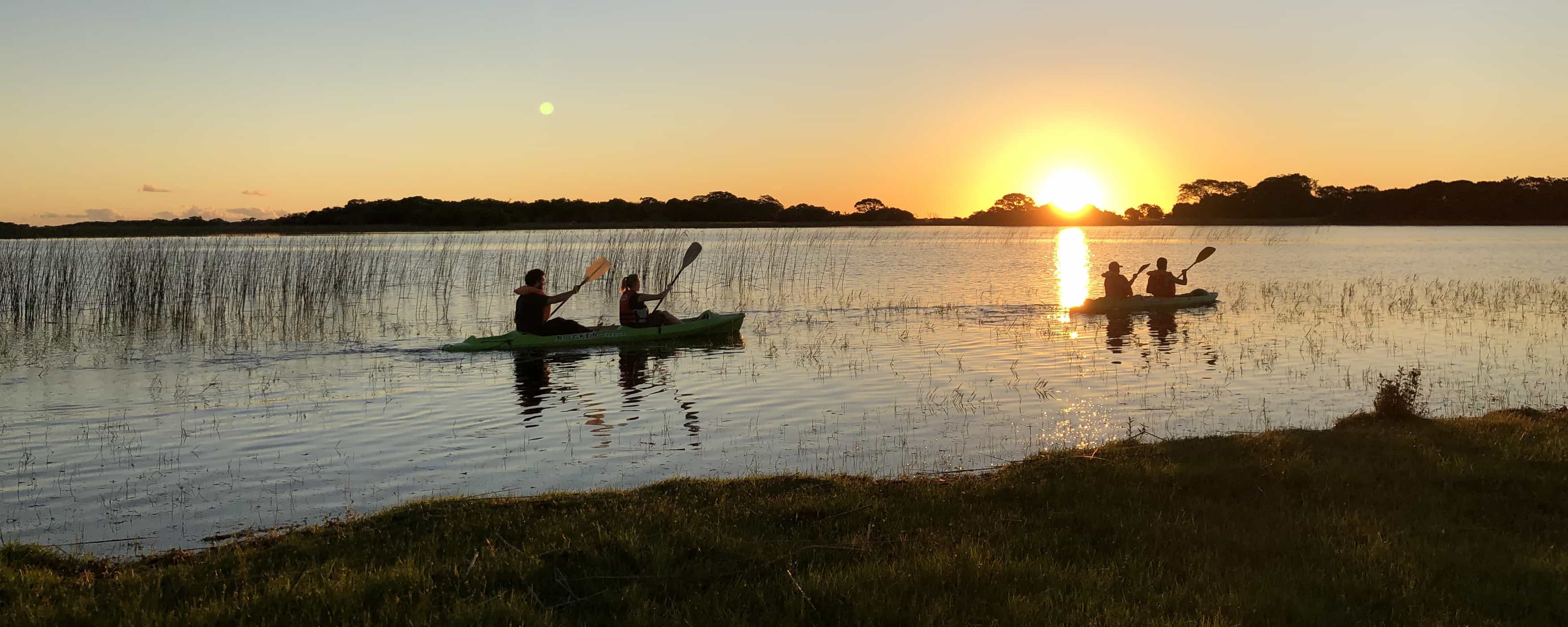 foto de personas en kayaks durante el atardecer
